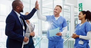 Healthcare hiring team celebrating with medical staff in a hospital after successful screening and credentialing.